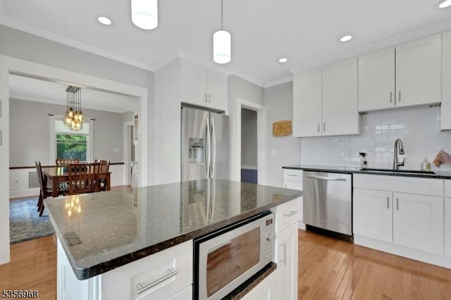 42 Mountain Ave, Mendham Boro, NJ 07945 - kitchen with appliances with stainless steel finishes, a sink, light wood-style floors, white cabinetry, and crown molding