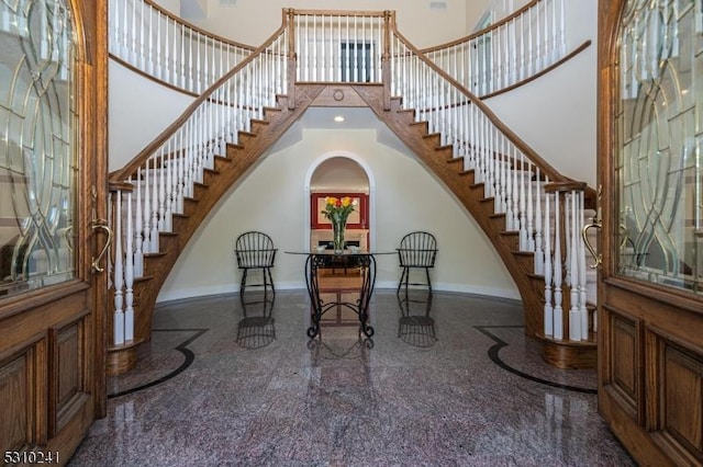 foyer featuring a high ceiling, baseboards, stairway, granite tiled floors, and inlaid floor details