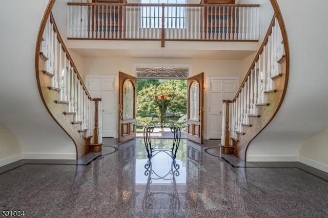 entrance foyer featuring granite tiled floors, baseboards, stairs, and a high ceiling