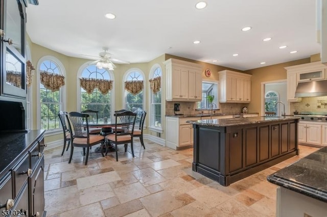 kitchen with recessed lighting, backsplash, dark stone countertops, and plenty of natural light