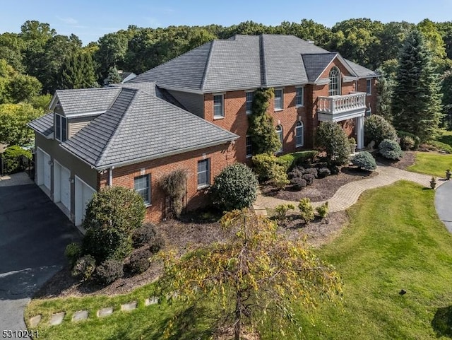 view of home's exterior with brick siding, asphalt driveway, a lawn, and a forest view