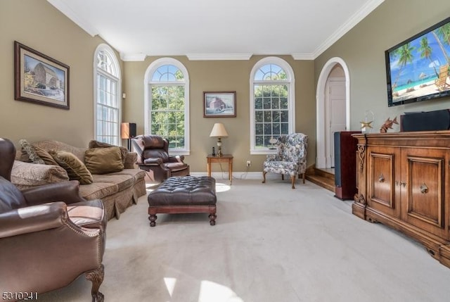 carpeted living room featuring ornamental molding, arched walkways, and baseboards
