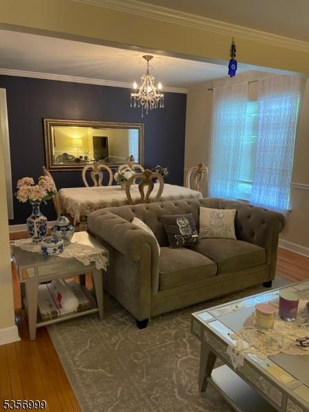 bedroom featuring wood finished floors, crown molding, baseboards, and a chandelier