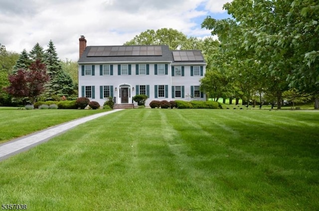 16 Dorset Ln, Andover Twp, NJ 07848 - colonial-style house with a chimney, roof mounted solar panels, and a front yard