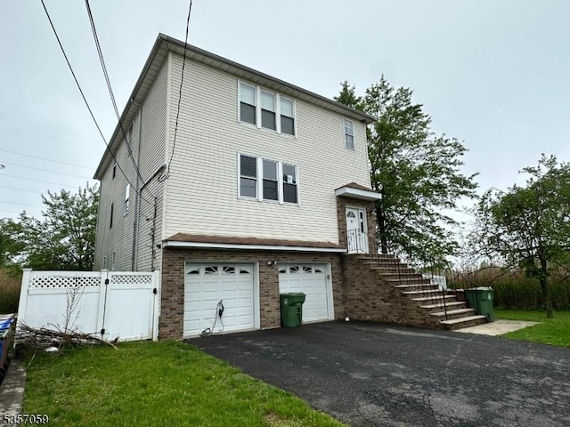 view of front of home with an attached garage, asphalt driveway, fence, and brick siding
