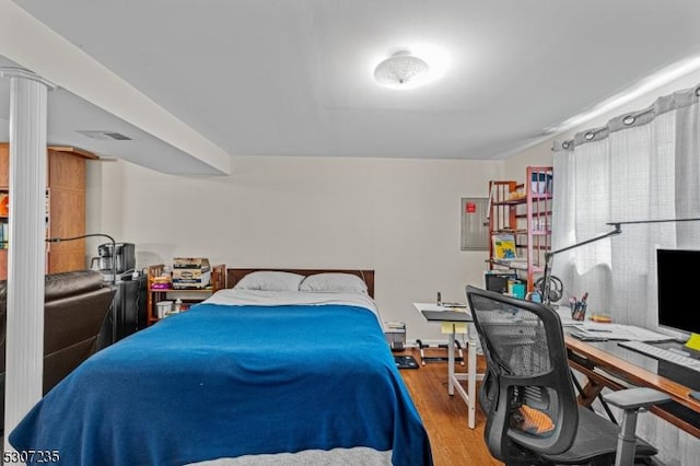 bedroom with wood finished floors and an office area