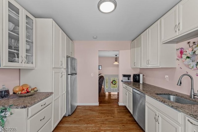 kitchen featuring appliances with stainless steel finishes, a sink, wood finished floors, and white cabinets