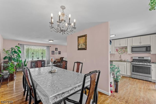dining area with a chandelier, light wood-style flooring, and baseboards
