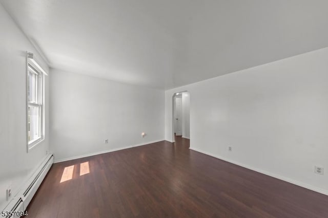 spare room featuring a baseboard radiator, dark wood finished floors, and baseboards