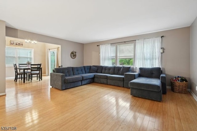 living room featuring light wood-type flooring, baseboards, and a chandelier