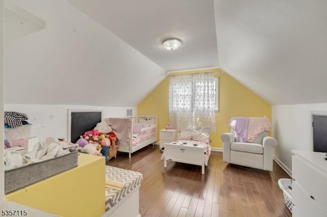 bedroom with wood-type flooring and vaulted ceiling