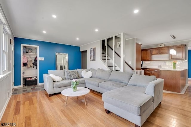 living area featuring light wood-style floors, radiator heating unit, recessed lighting, and stairway