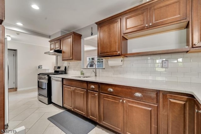 kitchen with stainless steel appliances, a sink, decorative backsplash, brown cabinetry, and recessed lighting