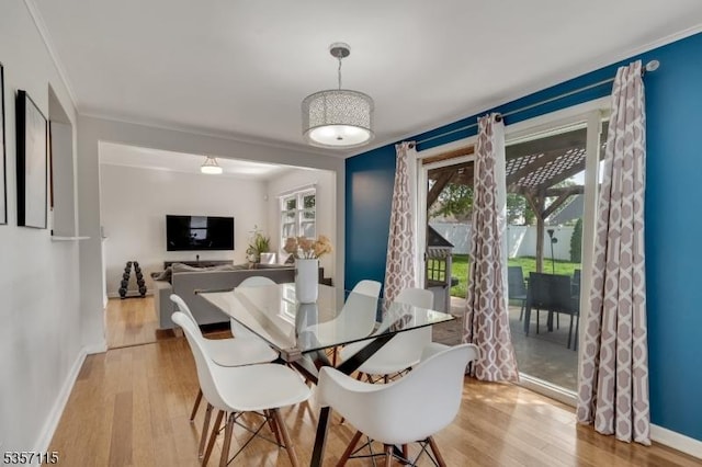 dining space with crown molding, light wood-style flooring, plenty of natural light, and baseboards