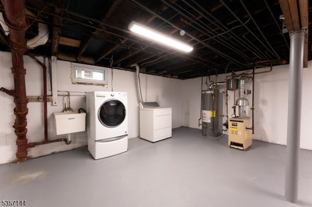 below grade area featuring independent washer and dryer, gas water heater, a sink, and a heating unit