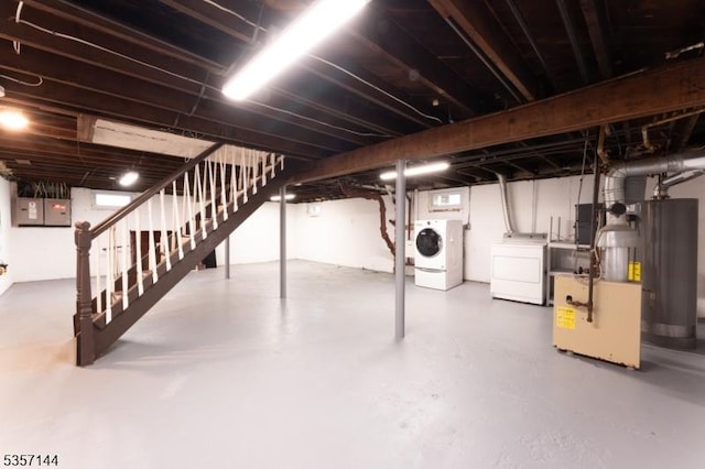 below grade area featuring washing machine and clothes dryer, stairs, electric panel, and gas water heater