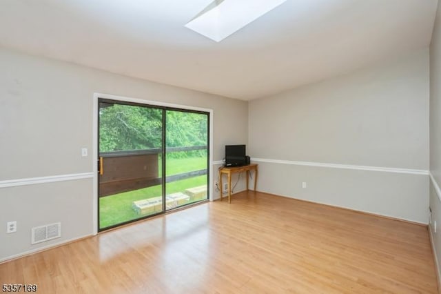 spare room with wood finished floors and a skylight
