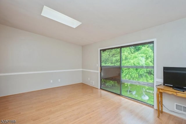unfurnished living room with wood finished floors and a skylight