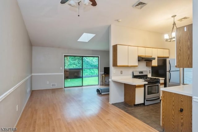 kitchen with stainless steel range with gas cooktop, light countertops, open floor plan, under cabinet range hood, and wood finished floors