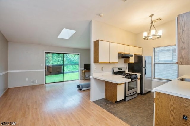 kitchen featuring appliances with stainless steel finishes, under cabinet range hood, a skylight, light countertops, and white cabinetry