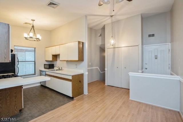 kitchen with a sink, light countertops, white cabinets, a chandelier, and decorative light fixtures