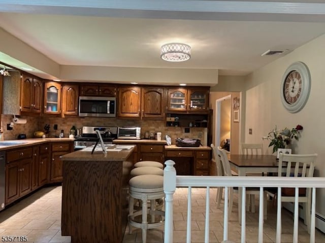 32 Northgate, Wanaque Boro, NJ 07465 - kitchen featuring appliances with stainless steel finishes, backsplash, a center island with sink, and glass insert cabinets