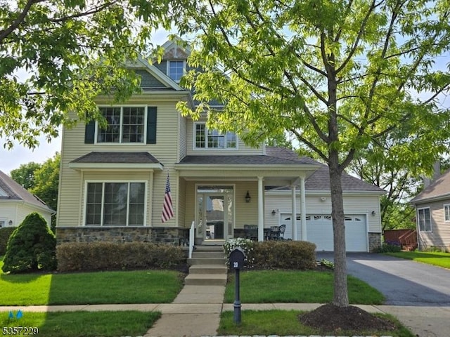 view of front of home with stone siding, a garage, covered porch, and a front yard