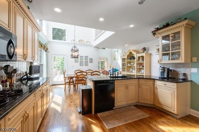 kitchen featuring black appliances, a sink, wood finished floors, a peninsula, and recessed lighting
