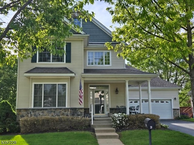 view of front of house with stone siding, asphalt driveway, a garage, a shingled roof, and covered porch