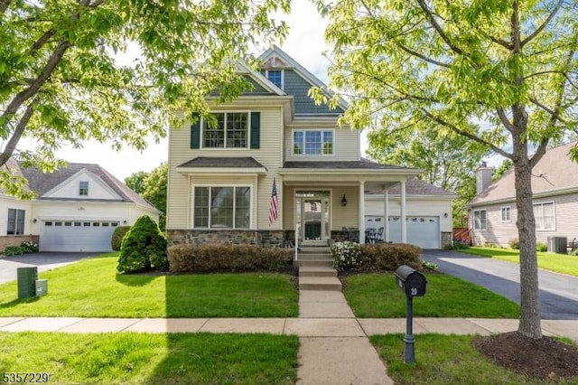 view of front facade featuring stone siding, a front yard, a garage, and central AC unit