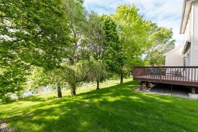 view of green lawn featuring a deck