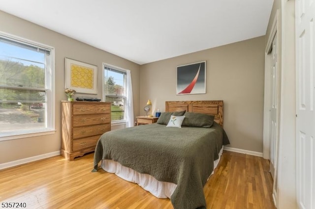 bedroom featuring light wood-type flooring, baseboards, and a closet