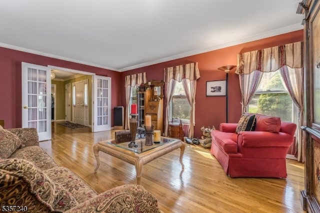 living area featuring french doors, healthy amount of natural light, ornamental molding, and wood finished floors