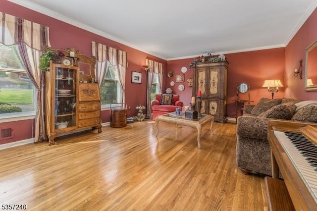 living area with light wood-style flooring, crown molding, and baseboards