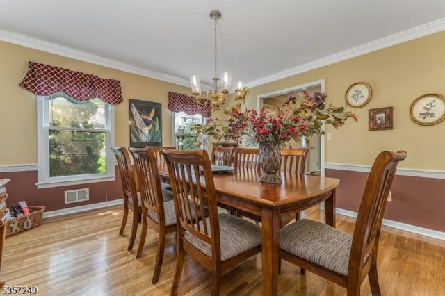 dining area with a chandelier, light wood-type flooring, crown molding, and baseboards