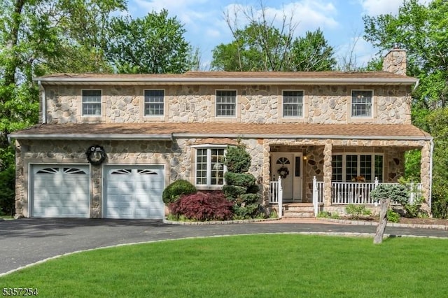 view of front of home with stone siding, a chimney, and asphalt driveway