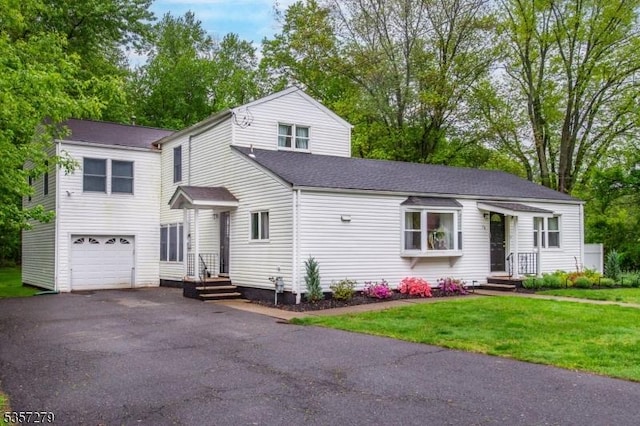 traditional-style house with a garage, asphalt driveway, a front yard, and a shingled roof