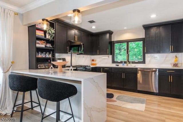 kitchen with stainless steel appliances, a sink, crown molding, a kitchen bar, and light wood-style floors
