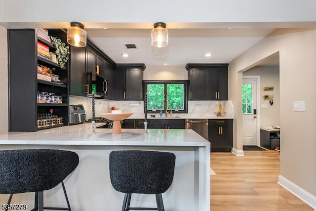 kitchen featuring stainless steel appliances, a kitchen breakfast bar, light countertops, decorative backsplash, and recessed lighting