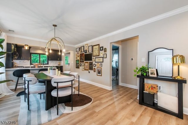 dining space featuring light wood-style flooring, crown molding, and baseboards