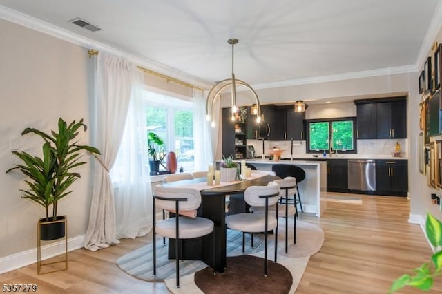 dining space featuring ornamental molding, light wood-style flooring, and baseboards