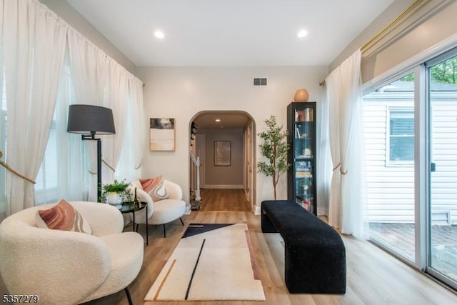 living area featuring arched walkways, light wood finished floors, recessed lighting, and baseboards