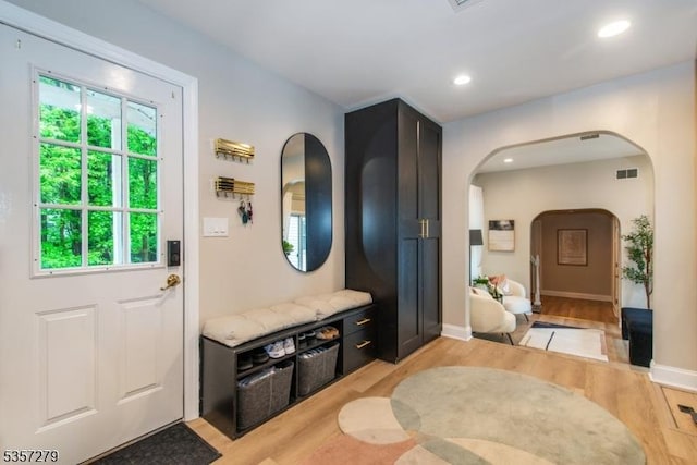 mudroom featuring arched walkways, light wood-style flooring, baseboards, and recessed lighting