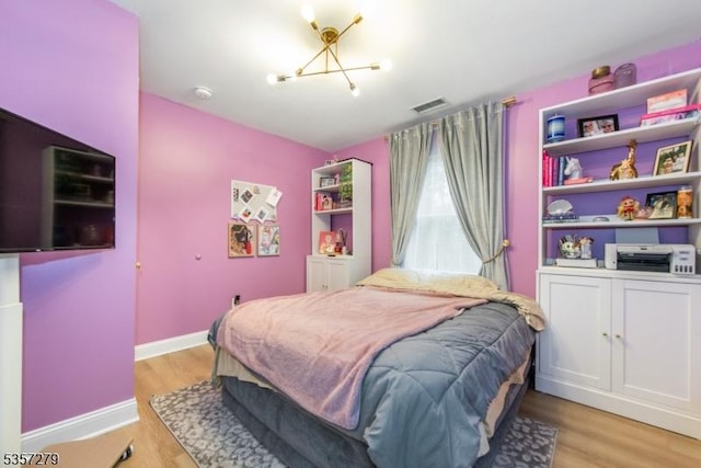 bedroom featuring light wood-type flooring, a chandelier, and baseboards