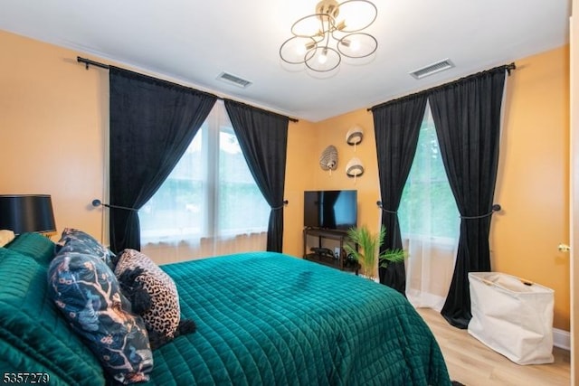 bedroom with a chandelier and light wood finished floors