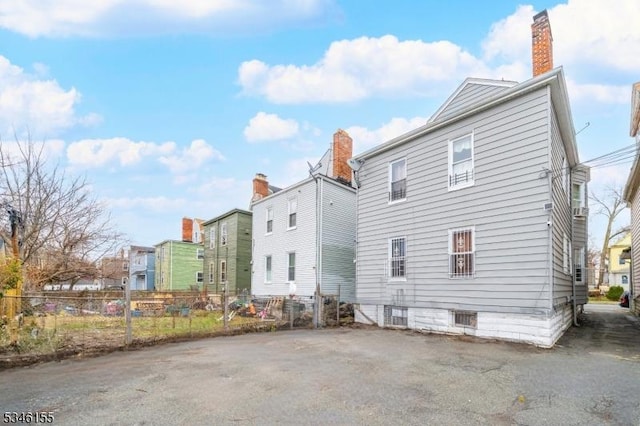 rear view of property featuring fence, a chimney, and a residential view