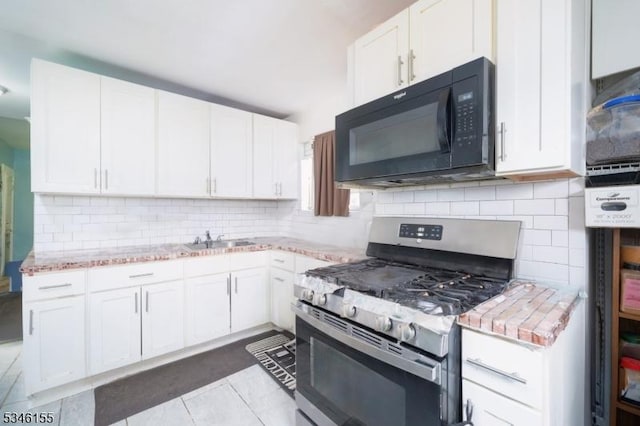 kitchen featuring black microwave, stainless steel gas stove, decorative backsplash, and white cabinets