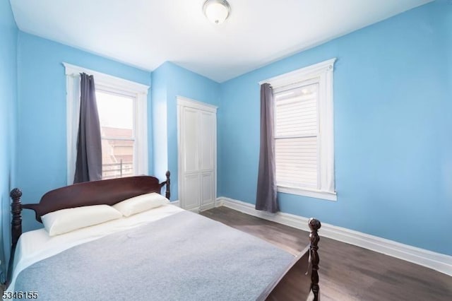 bedroom with baseboards, dark wood-style flooring, and a closet