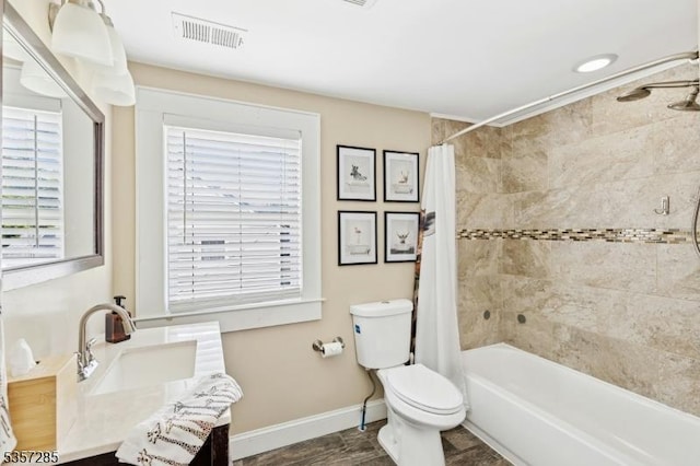 bathroom featuring toilet, shower / bath combo with shower curtain, baseboards, and vanity