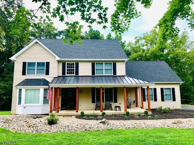 view of front of property with a standing seam roof, a shingled roof, a front lawn, and metal roof